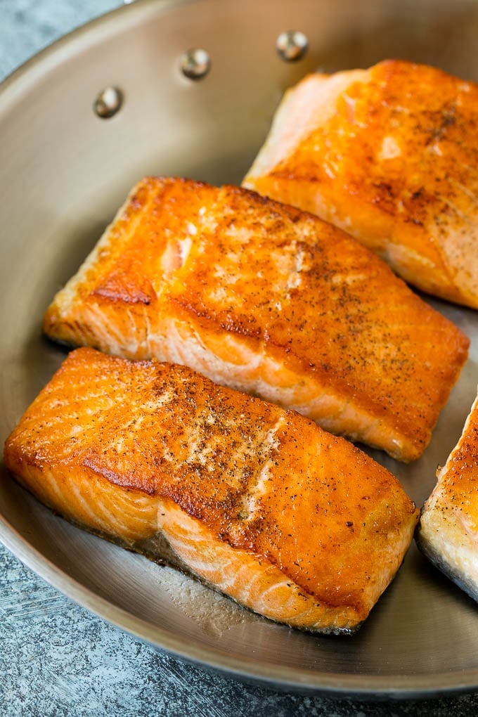 Seared salmon fillets in a pan.