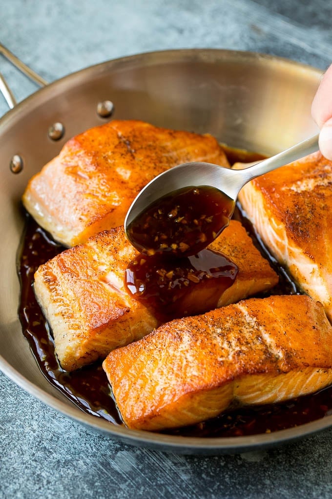 A spoon pouring honey glaze over salmon.