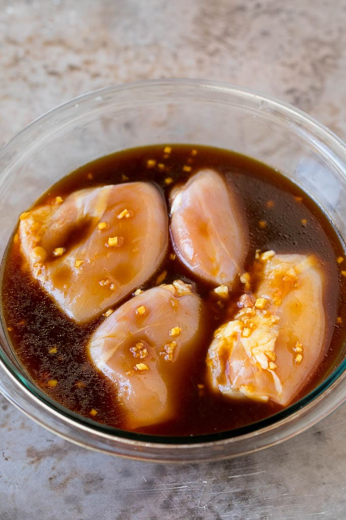 Chicken thighs in a bowl of marinade.