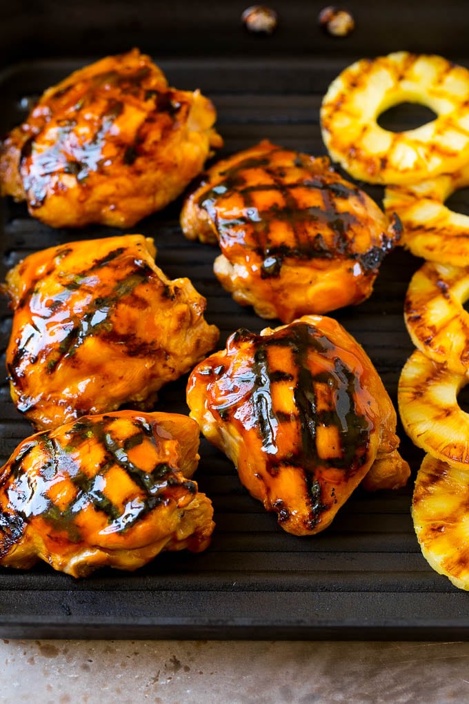 Chicken thighs and pineapple slices on a grill pan.