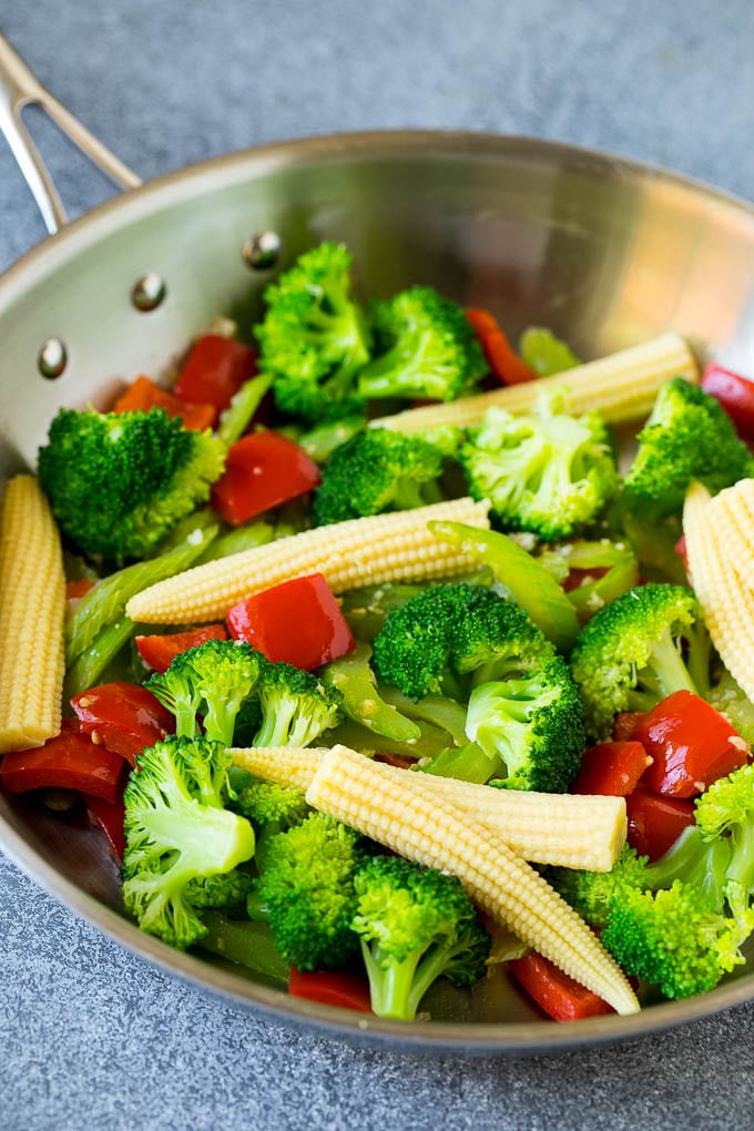 Broccoli florets, baby corn, bell peppers and celery in a skillet.