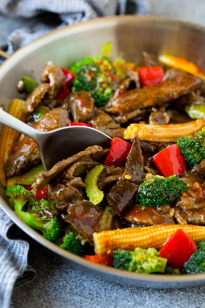 A serving spoon in a pan full of Hunan beef.