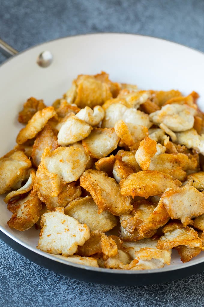 Thinly sliced chicken browned in a pan.