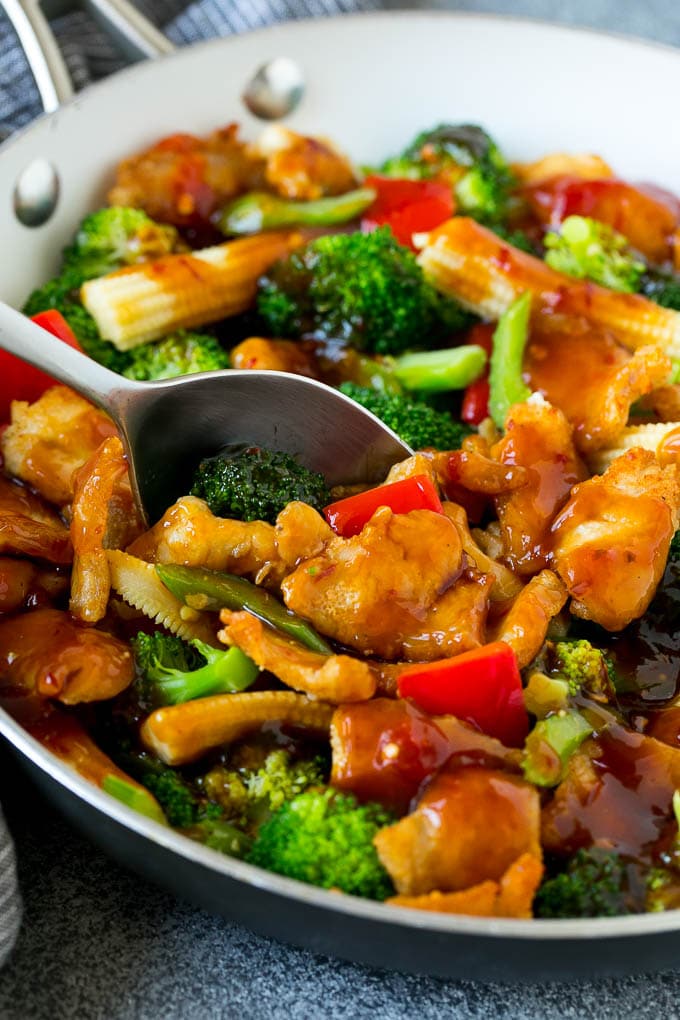 A spoon serving up a portion of spicy chicken stir fry.