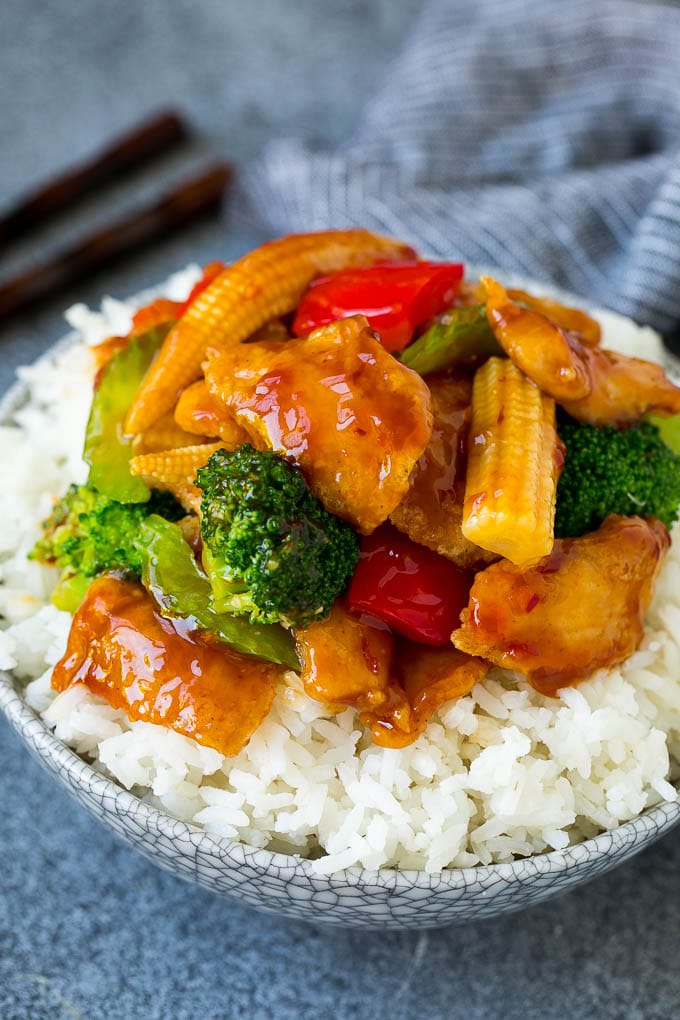 Hunan chicken with broccoli served over a bowl of rice.