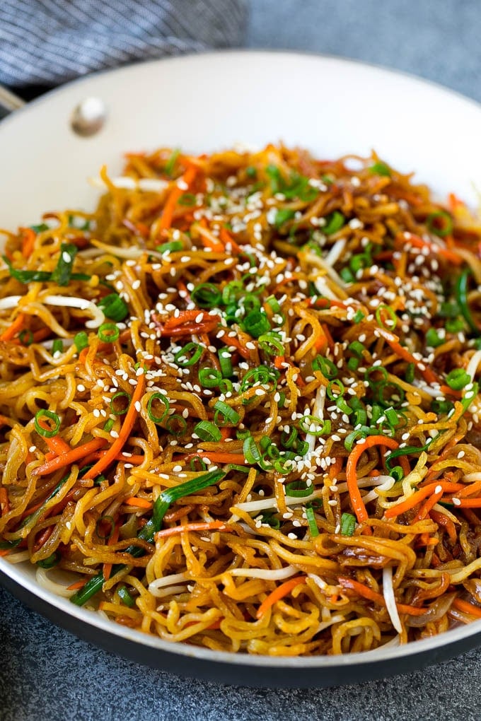 A skillet of pan fried noodles with carrots and bean sprouts.