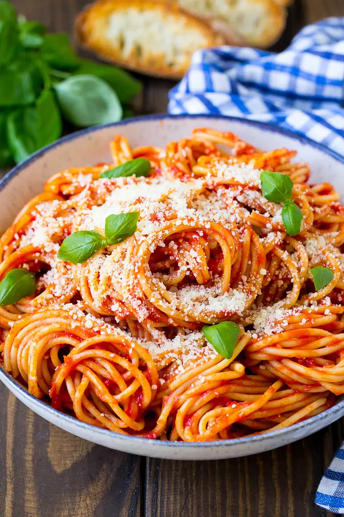 Pasta pomodoro topped with grated parmesan cheese and fresh basil leaves.