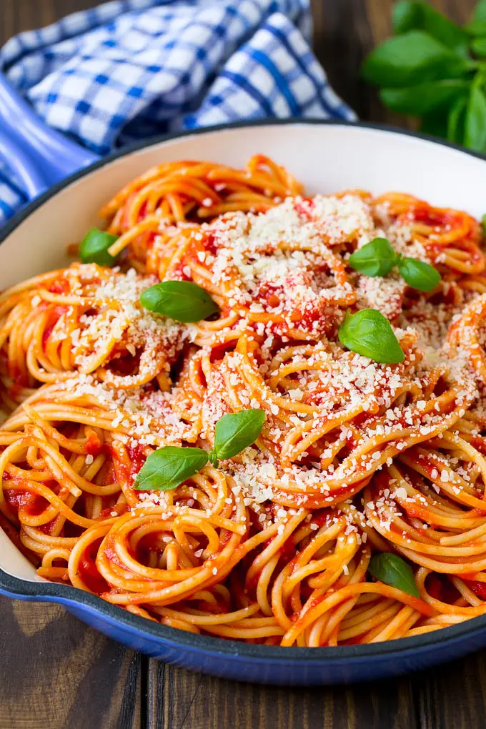 A pan of pasta pomodoro with cheese and fresh basil as garnish.