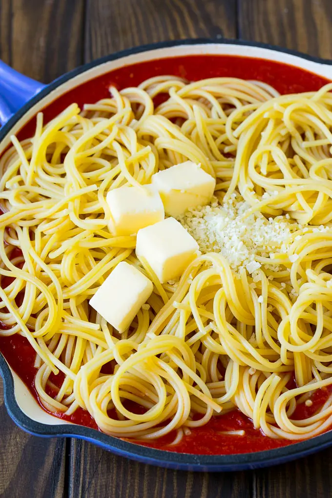 A skillet of tomato sauce with spaghetti, butter and cheese.