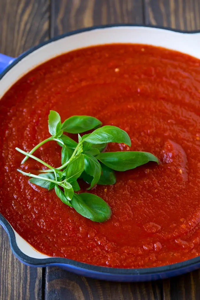 Homemade tomato sauce with fresh basil sprigs.