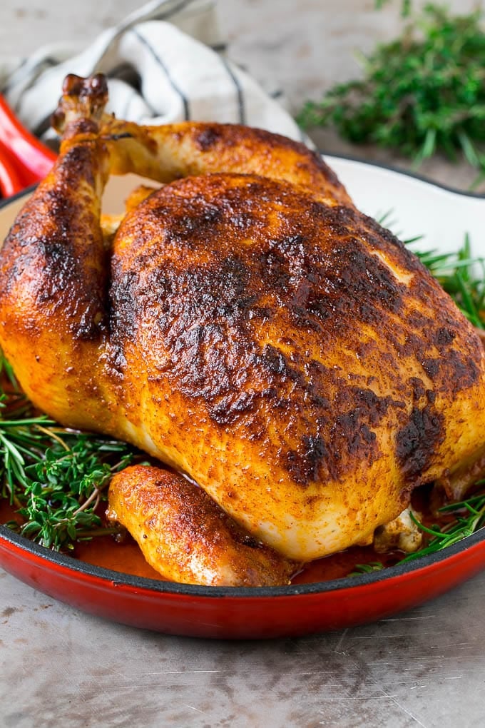 Rotisserie chicken in a skillet garnished with fresh herbs.