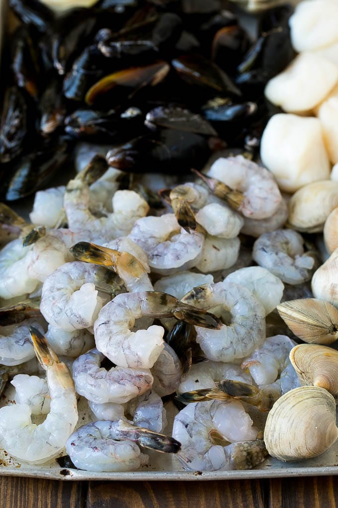 Raw shrimp, mussels, clams and scallops on a sheet pan.