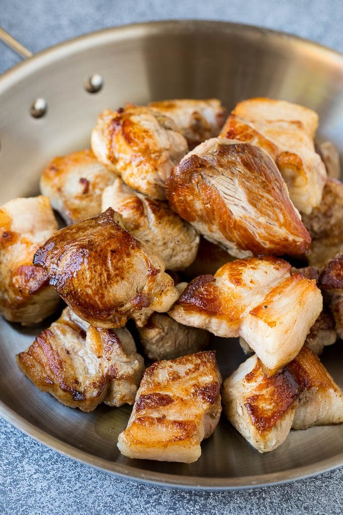 Chunks of browned pork in a skillet.