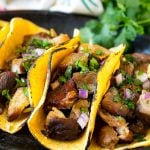 Slow cooker carnitas tacos filled with meat, onions and cilantro.