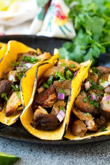 Slow cooker carnitas tacos filled with meat, onions and cilantro.