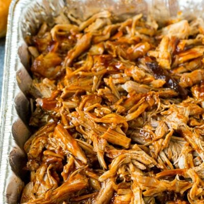 Smoked pulled pork in a metal tray with BBQ sauce.