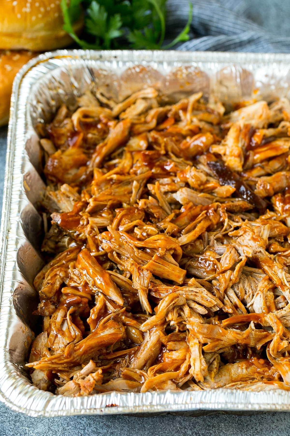 Smoked pulled pork in a metal tray with BBQ sauce.