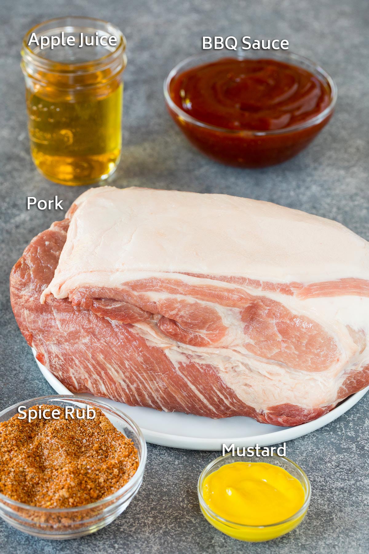 Pork shoulder and bowls of BBQ rub, sauce, mustard and apple juice.