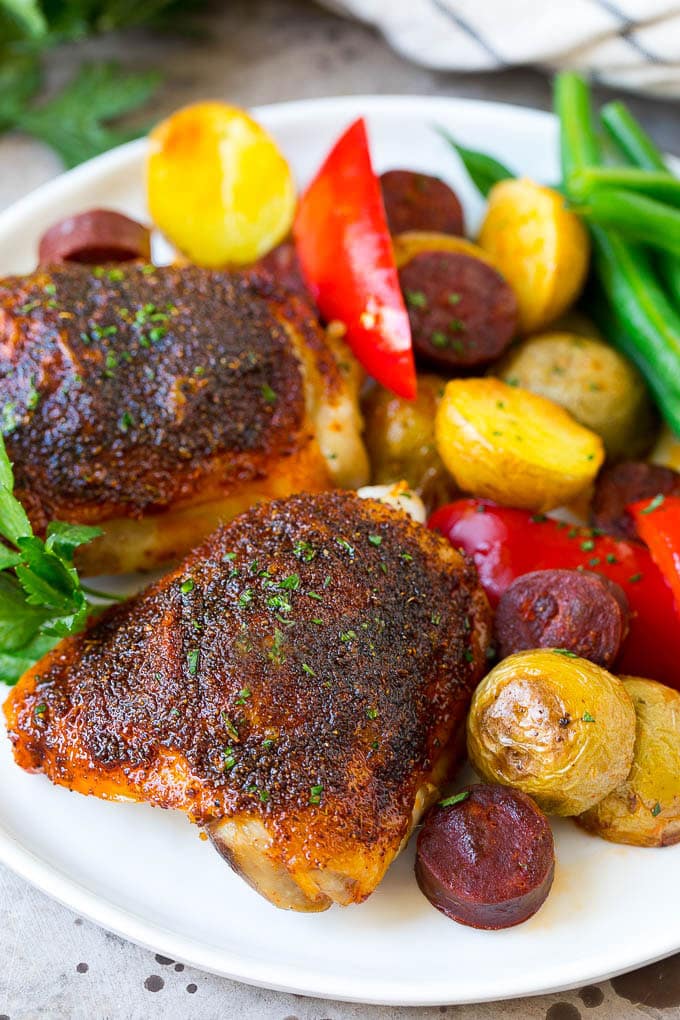 A plate of Spanish chicken with potatoes, sausage and vegetables.