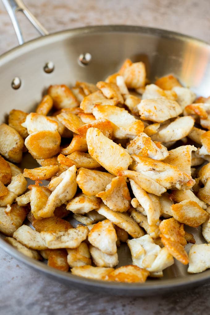 Thinly sliced chicken seared in a skillet.