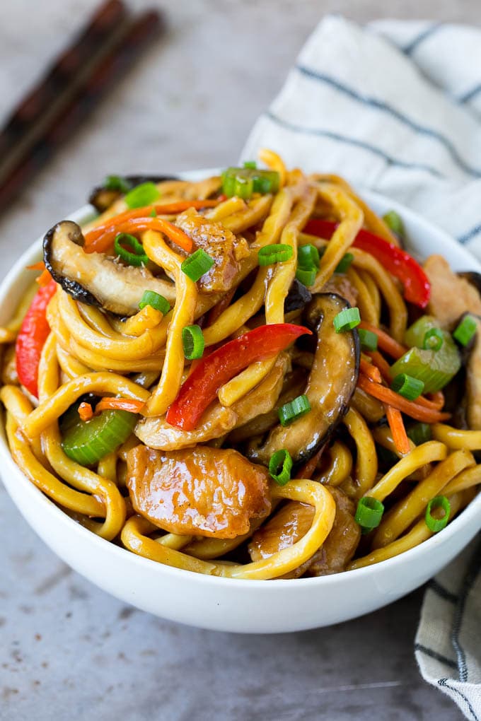 A bowl of stir fry noodles with chicken and vegetables.