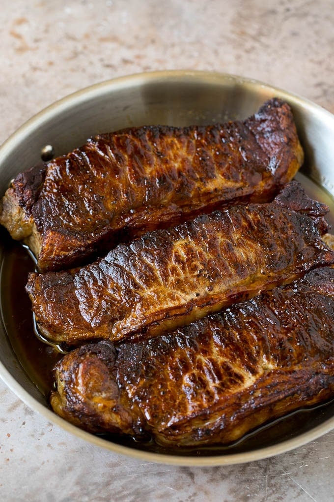 Seared strip steaks in a skillet.