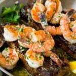 Surf and turf with seared strip steaks topped with jumbo shrimp.