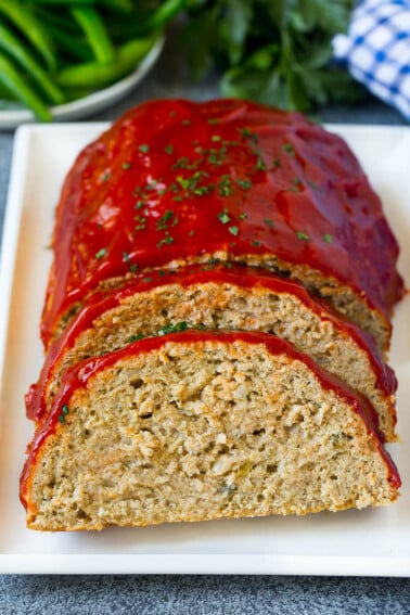 A sliced turkey meatloaf topped with ketchup and chopped parsley.