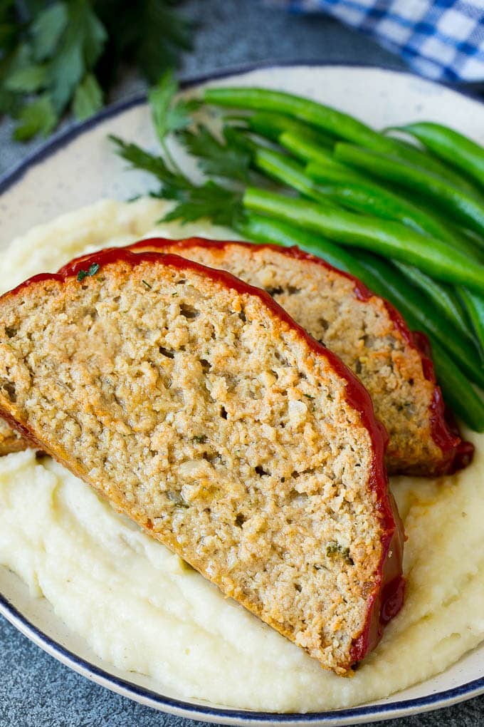 Sliced turkey meatloaf served over mashed potatoes with green beans.