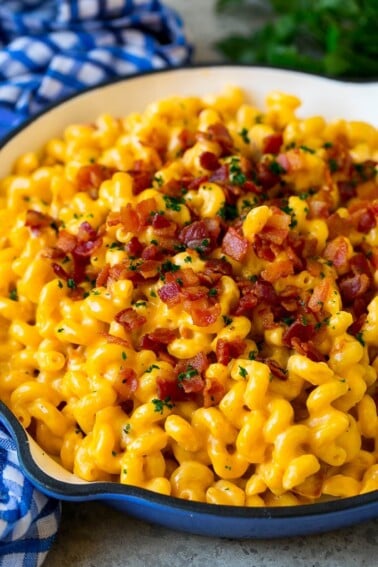 Bacon mac and cheese in a skillet, garnished with chopped parsley.