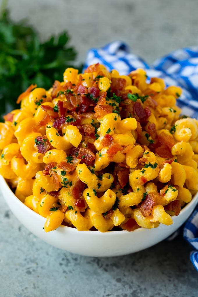 A bowl of bacon mac and cheese topped with chopped parsley.