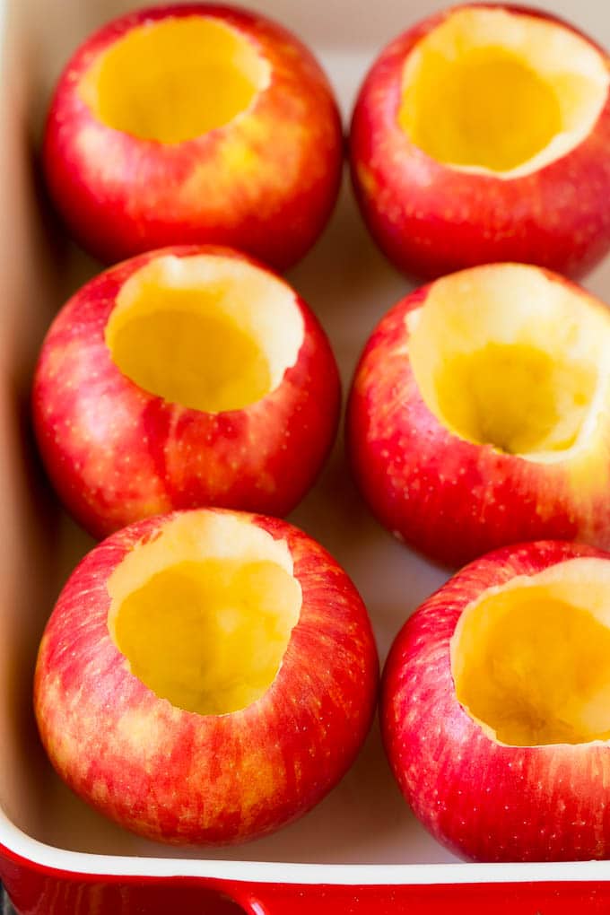 Hollowed out apples in a baking dish.