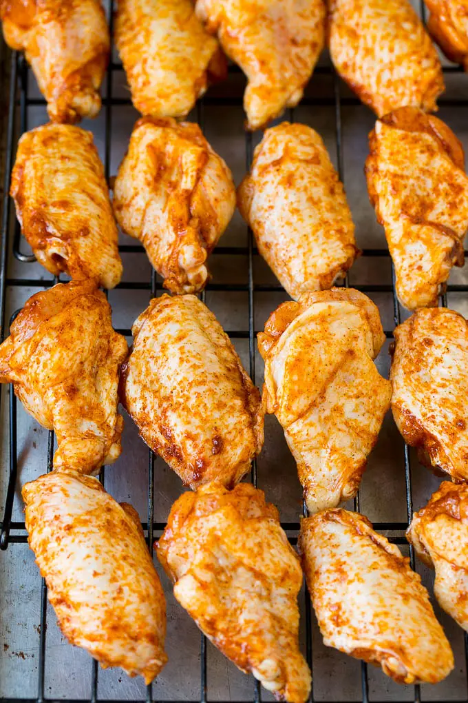 Spice coated chicken wings on a baking rack.