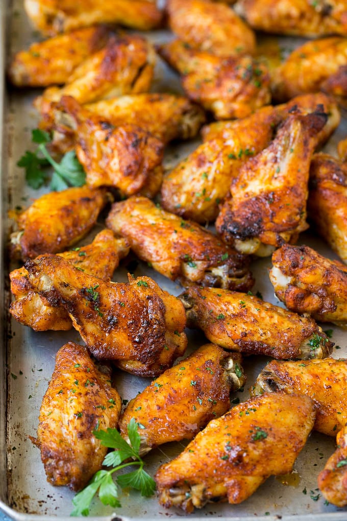 Baked chicken wings on a sheet pan, topped with parsley.
