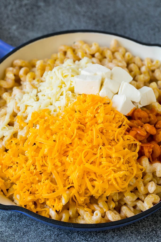 Cooked pasta topped with shredded cheese, cream cheese and hot sauce.