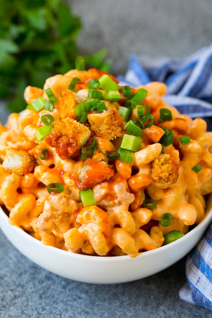 A bowl of buffalo chicken mac and cheese garnished with celery and green onions.