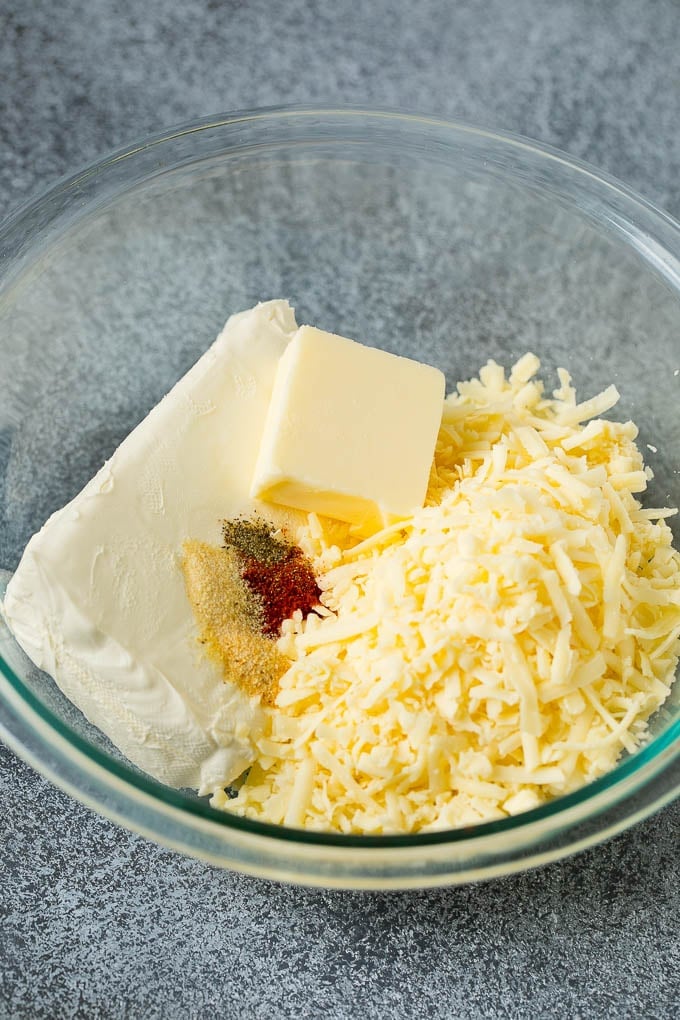 Shredded cheese, cream cheese, butter and spices in a mixing bowl.