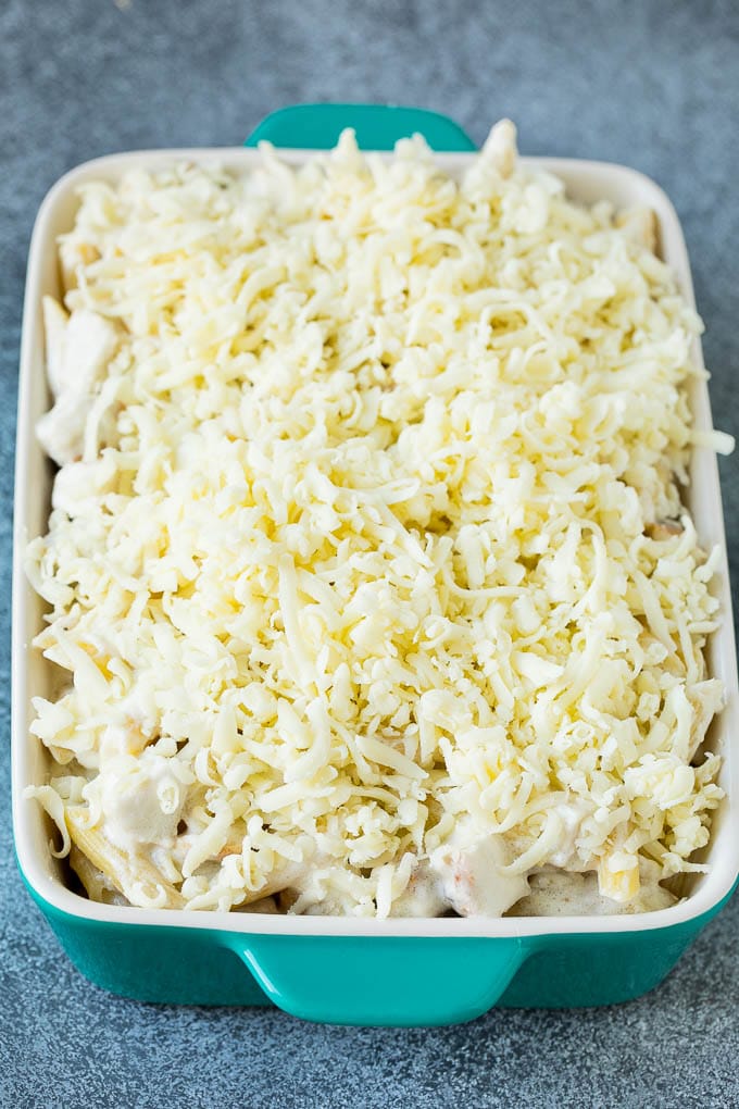 Creamy pasta in a baking dish topped with shredded cheese.