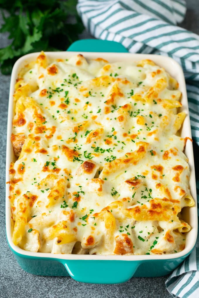Chicken Alfredo bake with penne pasta in a creamy sauce, topped with melted cheese.