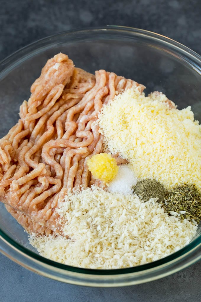 Ground chicken, herbs, breadcrumbs and cheese in a mixing bowl.