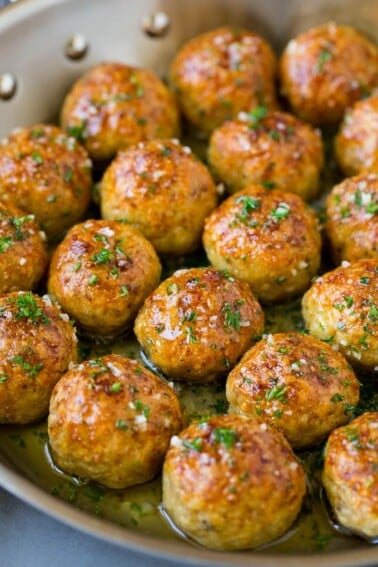 Chicken meatballs in a skillet of garlic butter.