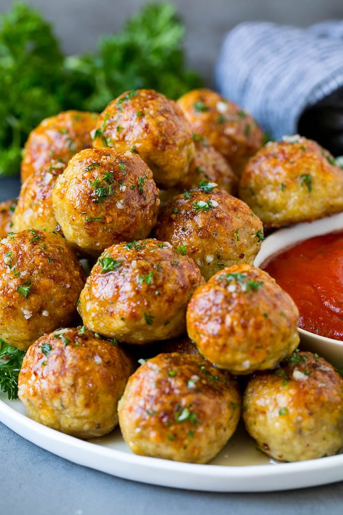 A serving plate of chicken meatballs served with marinara sauce.