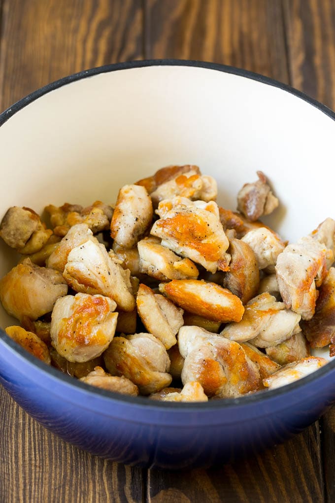 Seared chicken thigh pieces in a soup pot.