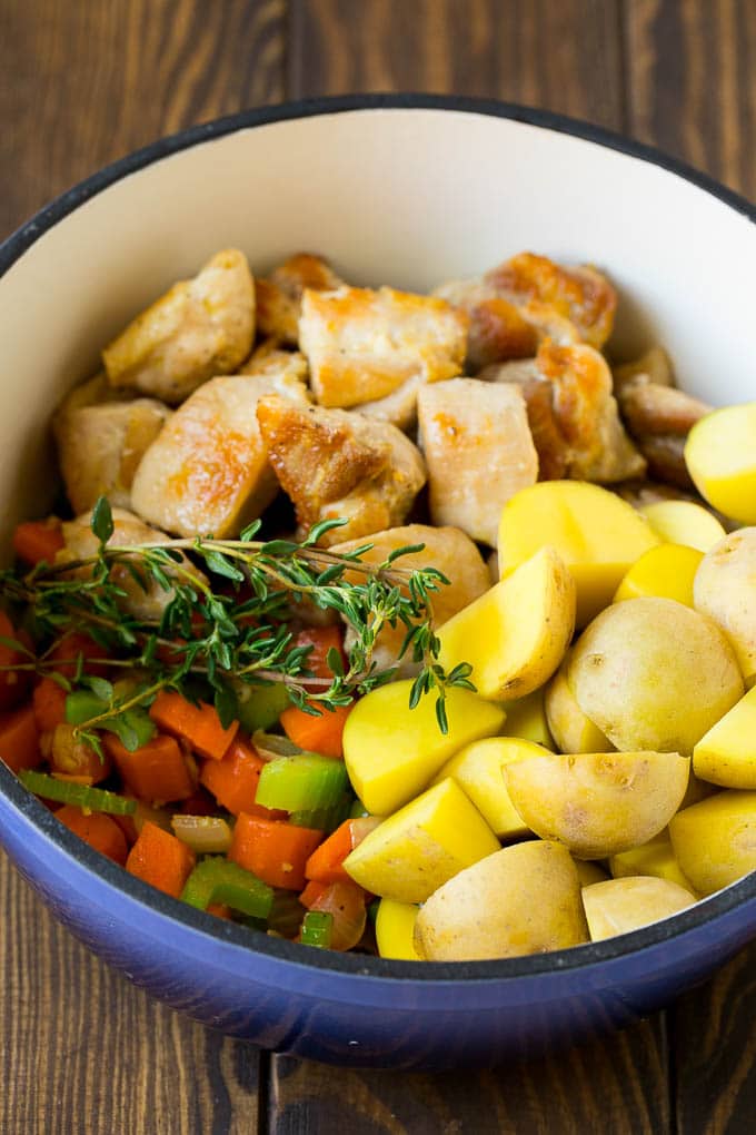 Seared chicken, vegetables and potatoes in a soup pot.