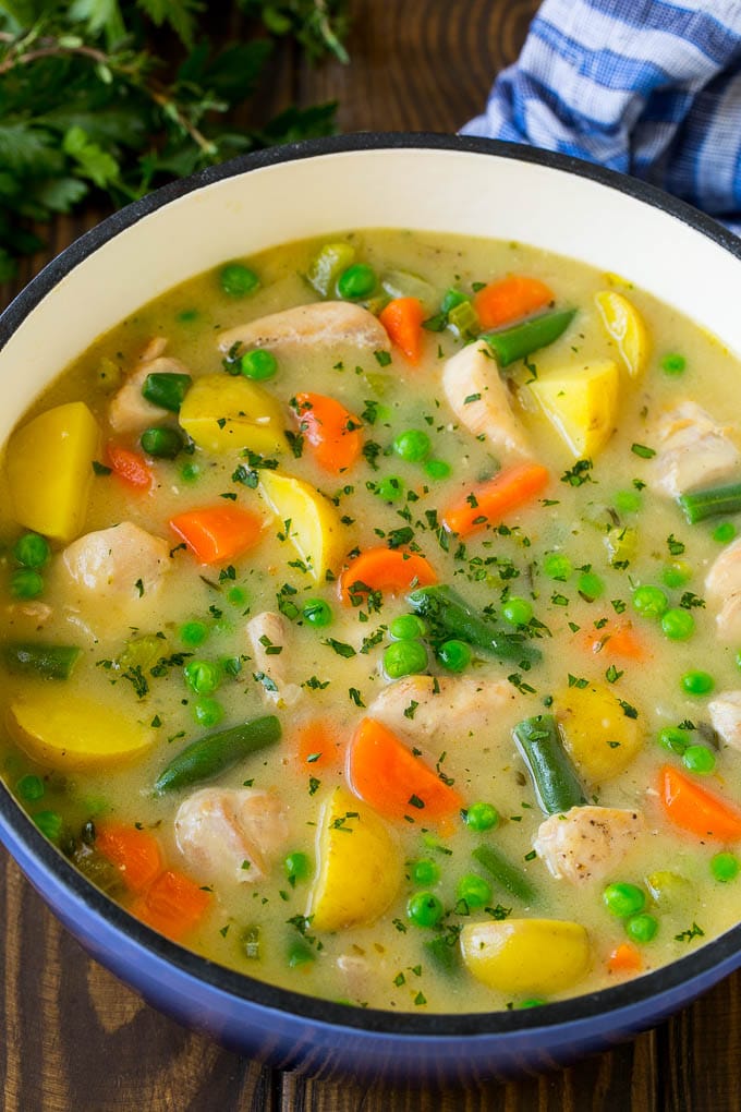 A pot of chicken stew with potatoes, carrots and peas.