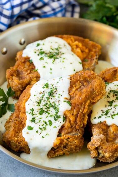 Fried pork chops topped with creamy gravy and parsley.
