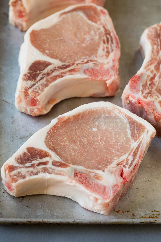 Raw pork chops on a sheet pan.