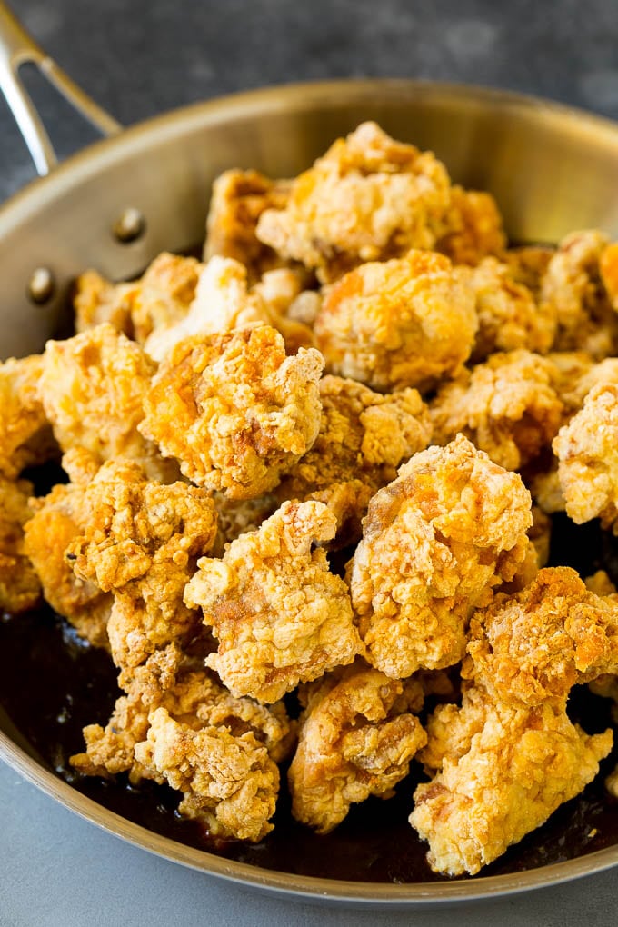 Crispy chicken in a skillet filled with savory and spicy sauce.