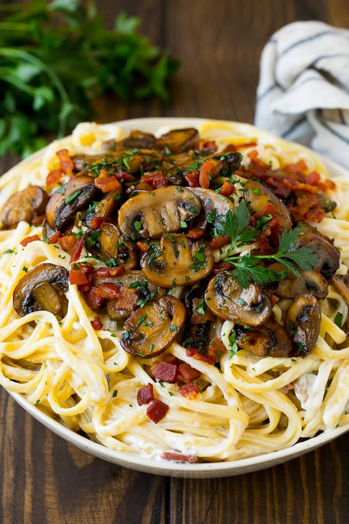 A bowl of creamy mushroom pasta topped with bacon.