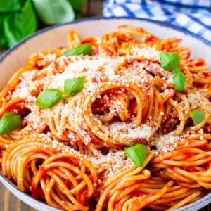 A serving bowl of pasta pomodoro garnished with fresh basil.